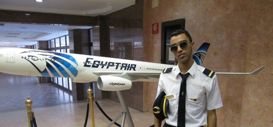 Subject in pilot uniform beside a model aircraft bearing EgyptAir branding