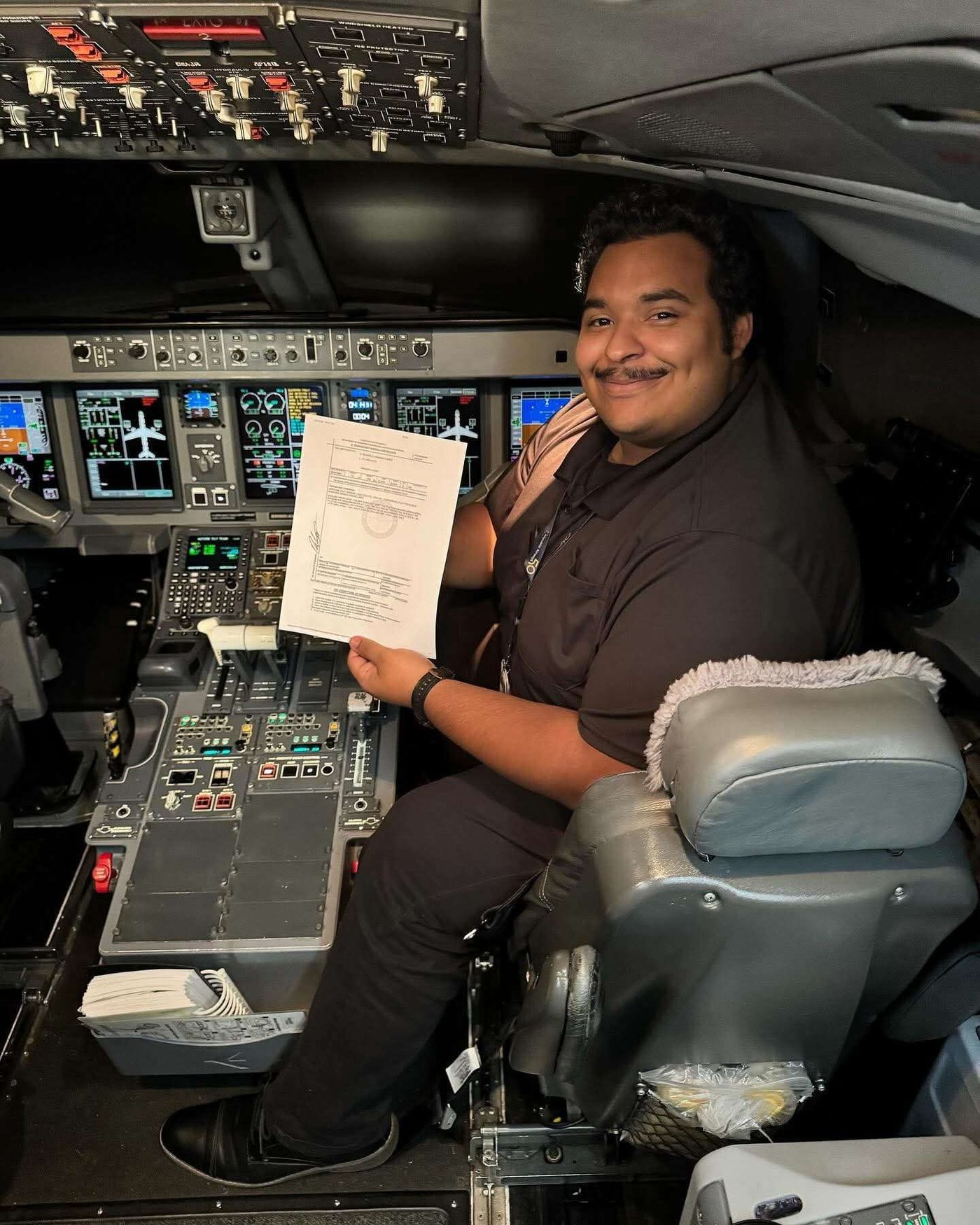 Photo from the fundraiser gallery: Ricardo Roman-Flores seated in an airline cockpit holding a document